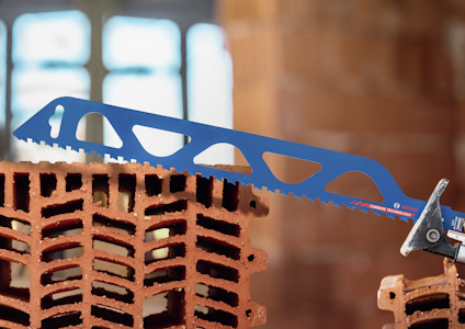 Blå såg med tandad klinga skär genom rött tegel i en byggnadsmiljö.