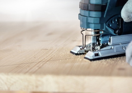 Sticksåg skär genom trä, närbild av sågblad och verktyg.