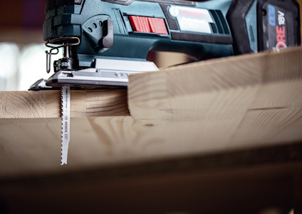 Sticksåg som skär genom en träskiva, med ett Bosch sågblad.