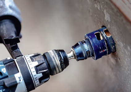 Borrmaskin med hålsåg borrar i betongvägg.