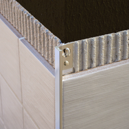 Kakelplatta fäst i vägghörn med metallprofil.