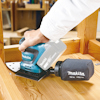 En person använder en Makita planslipmaskin på en träyta med dammpåse märkt "PART NO. 166078-4".