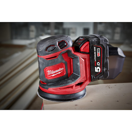 Röd och svart Milwaukee slipmaskin på ett bord inomhus, med 5.0 Lithium-ion batteri.