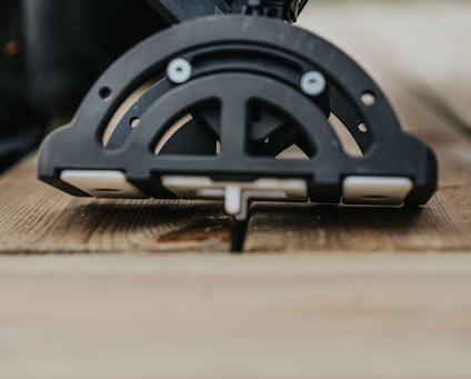 Svart verktyg för montering av trallbrädor på en träyta, sedd från sidan.