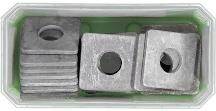 Fyrkantiga metallbrickor med cirkulärt hål, staplade i en plastbehållare.