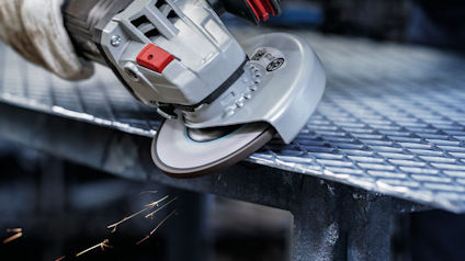 Närbild på en vinkelslip som slipar en metallgaller, gnistor flyger.