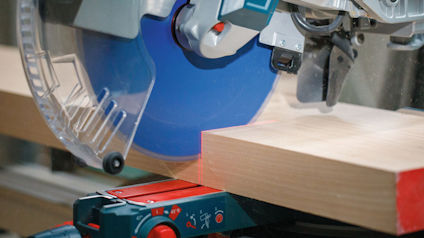 Cirkelsåg som skär genom en träplanka, blått sågblad och skyddshölje synligt.