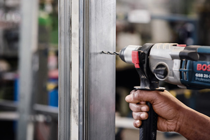 En person borrar ett hål i en metallbalk med en elektrisk borrmaskin.