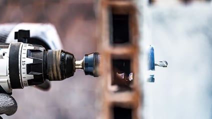 Borrmaskin med borr som borrar genom tegelvägg.