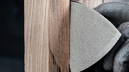 Händer i handskar formpressar tyg mot en träyta.